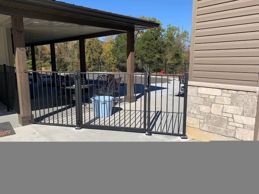 A metal fence is surrounding a parking lot next to a building.