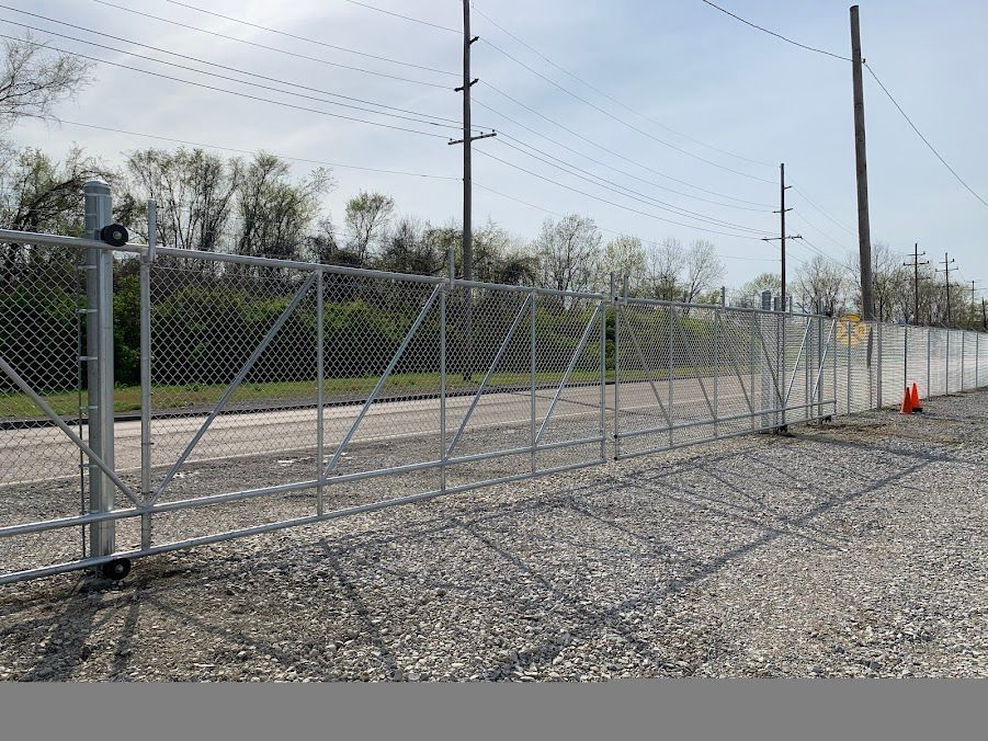 A chain link fence is surrounding a gravel road.