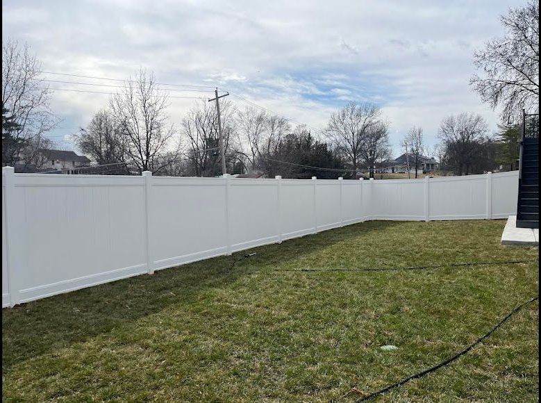 A white fence surrounds a lush green yard.