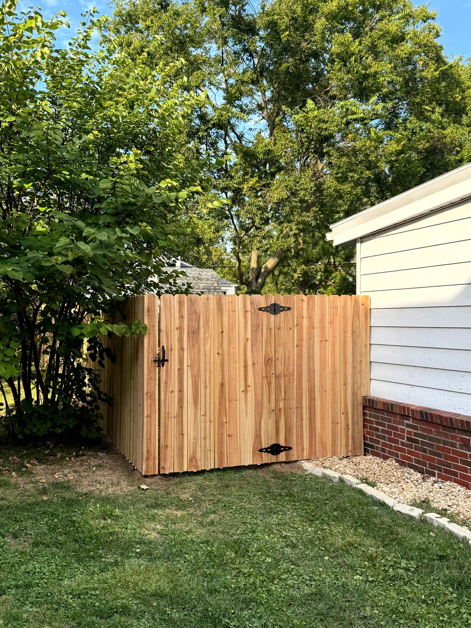 Backyard deck with white pergola, black railing, and steps, next to a tan house.