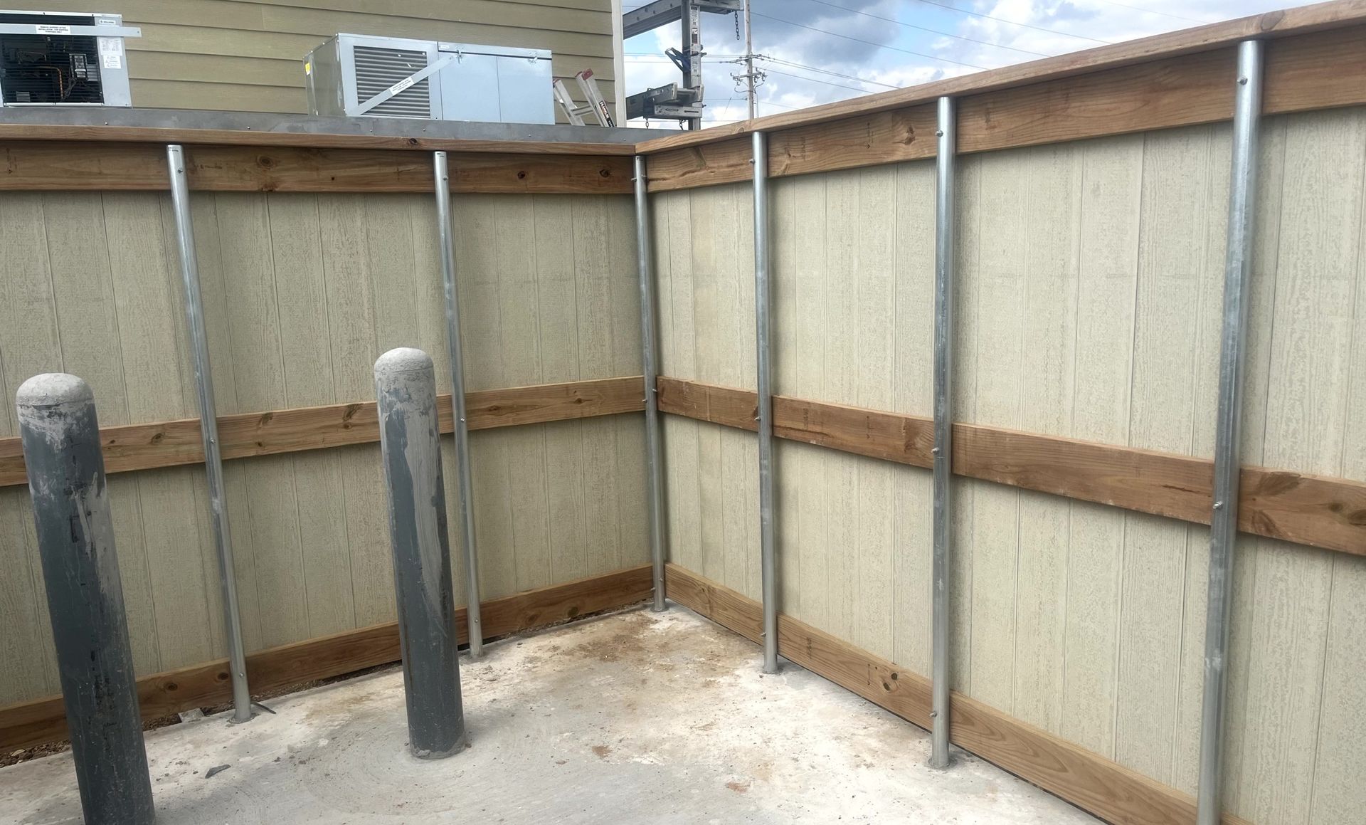 Custom dumpster enclosure built against commercial building for waste containment