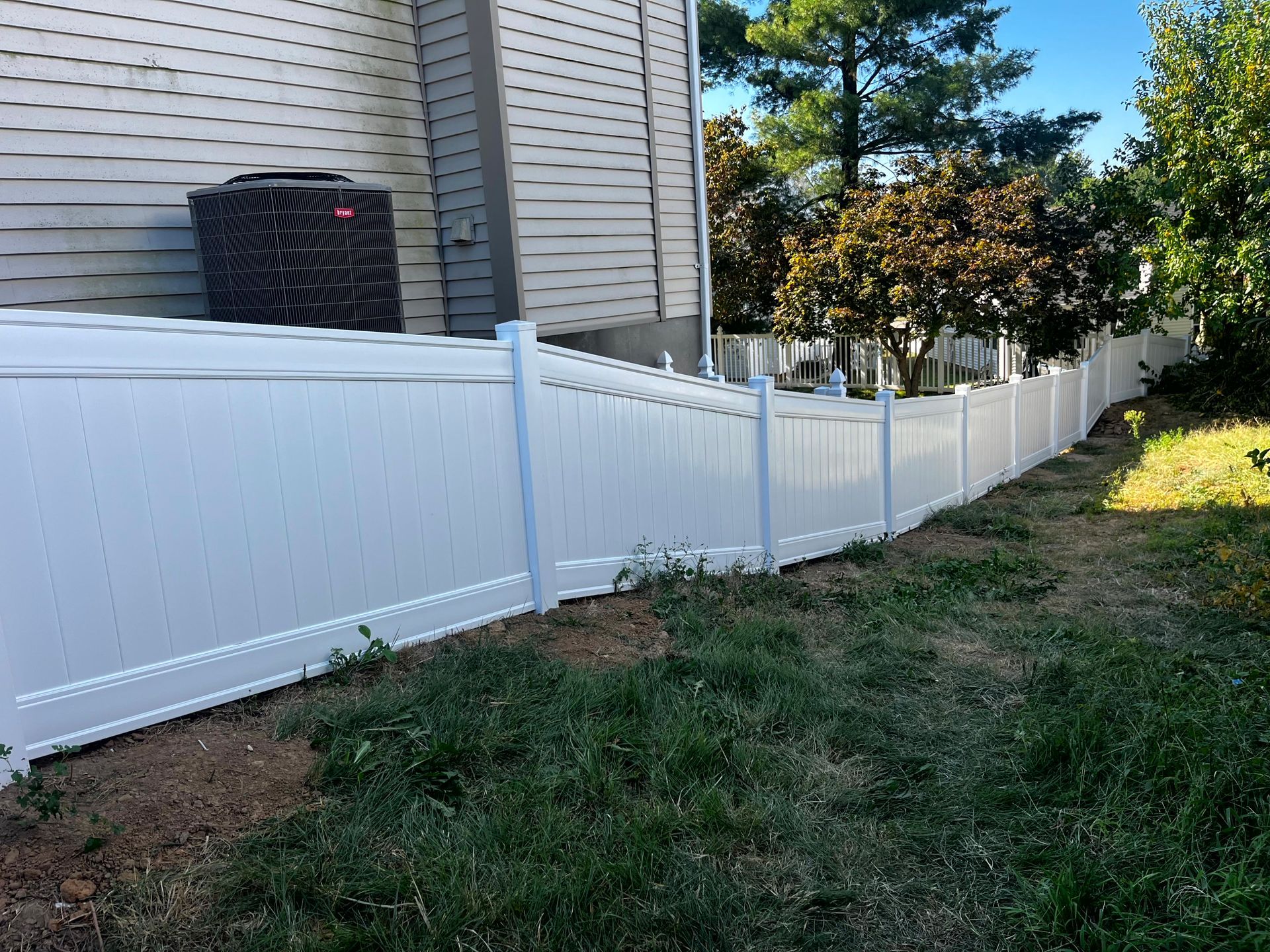 Black metal fence with small gate, green grass, and a building in the background.
