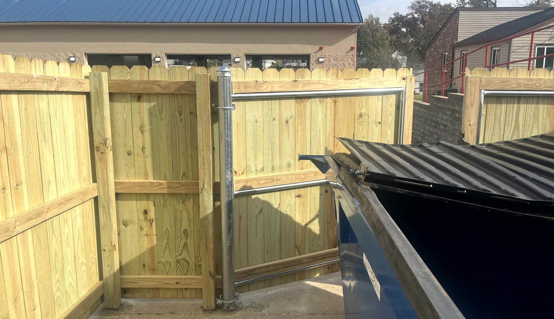 Wood dumpster enclosure with access gate for commercial waste collection