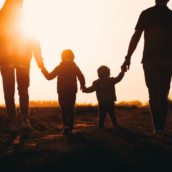 Family walking into the sunset holding hands