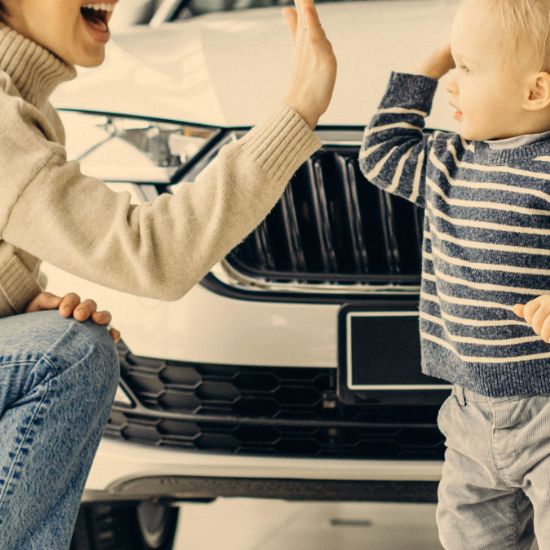 mother and child high fiving in front of new car