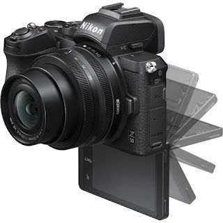 A black nikon camera is sitting on a white surface.