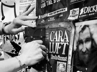 A black and white photo of a person reaching for a sign that says cara luft