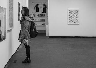 A woman is looking at a painting in a museum.