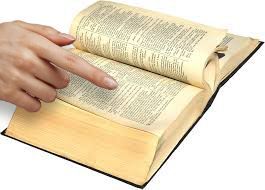 A person is pointing at a page in a book, possibly a dictionary, sitting on a white background.