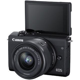 A canon eos camera is sitting on a white surface.