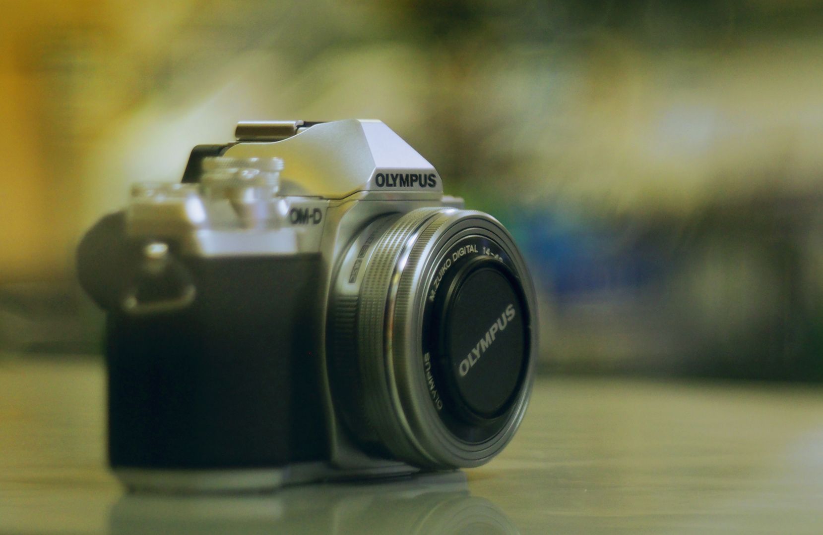 A black and white olympus camera is sitting on a table.