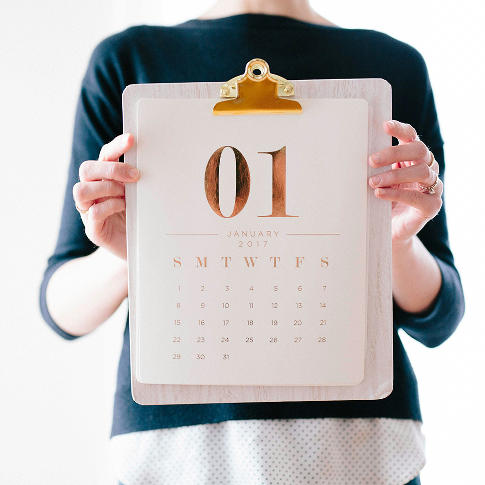 A woman is holding a poster calendar on a clipboard for January