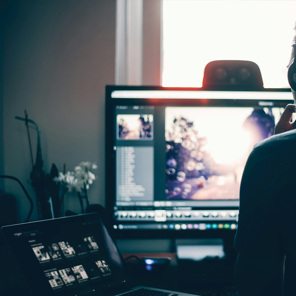 A person is sitting in front of a computer screen with the time 6:55 on it