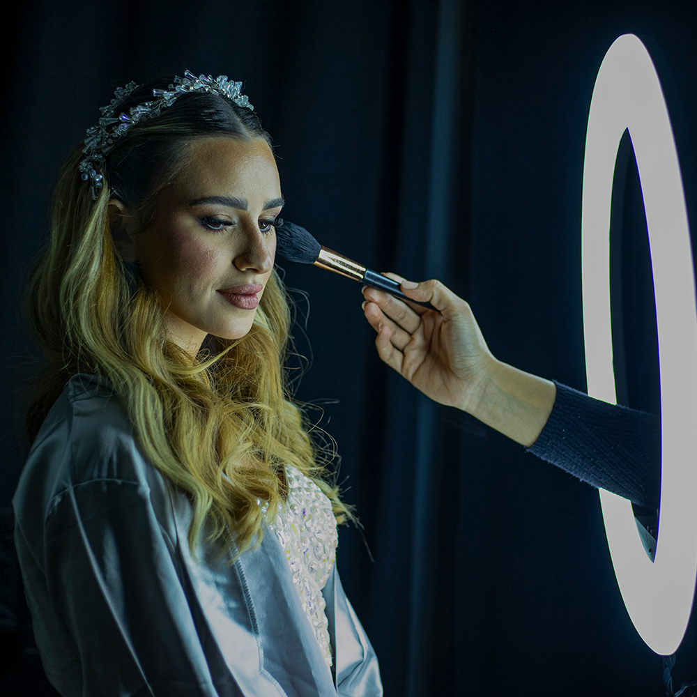 A woman is getting her makeup done in front of a ring light.