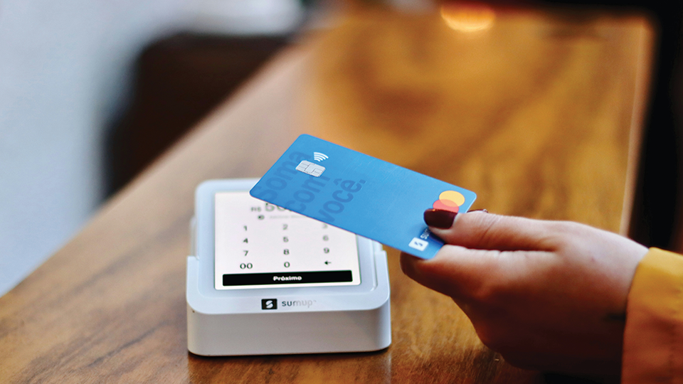 A person is holding a credit card in front of a credit card reader.