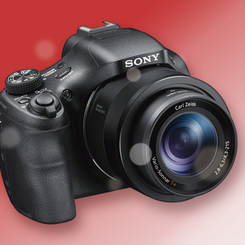 A sony camera with a carl zeiss lens in front of a gradient red to white background with Bokeh effects
