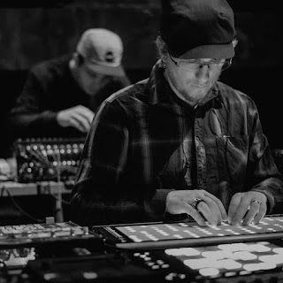 A man is sitting at a table playing a keyboard in a black and white photo.