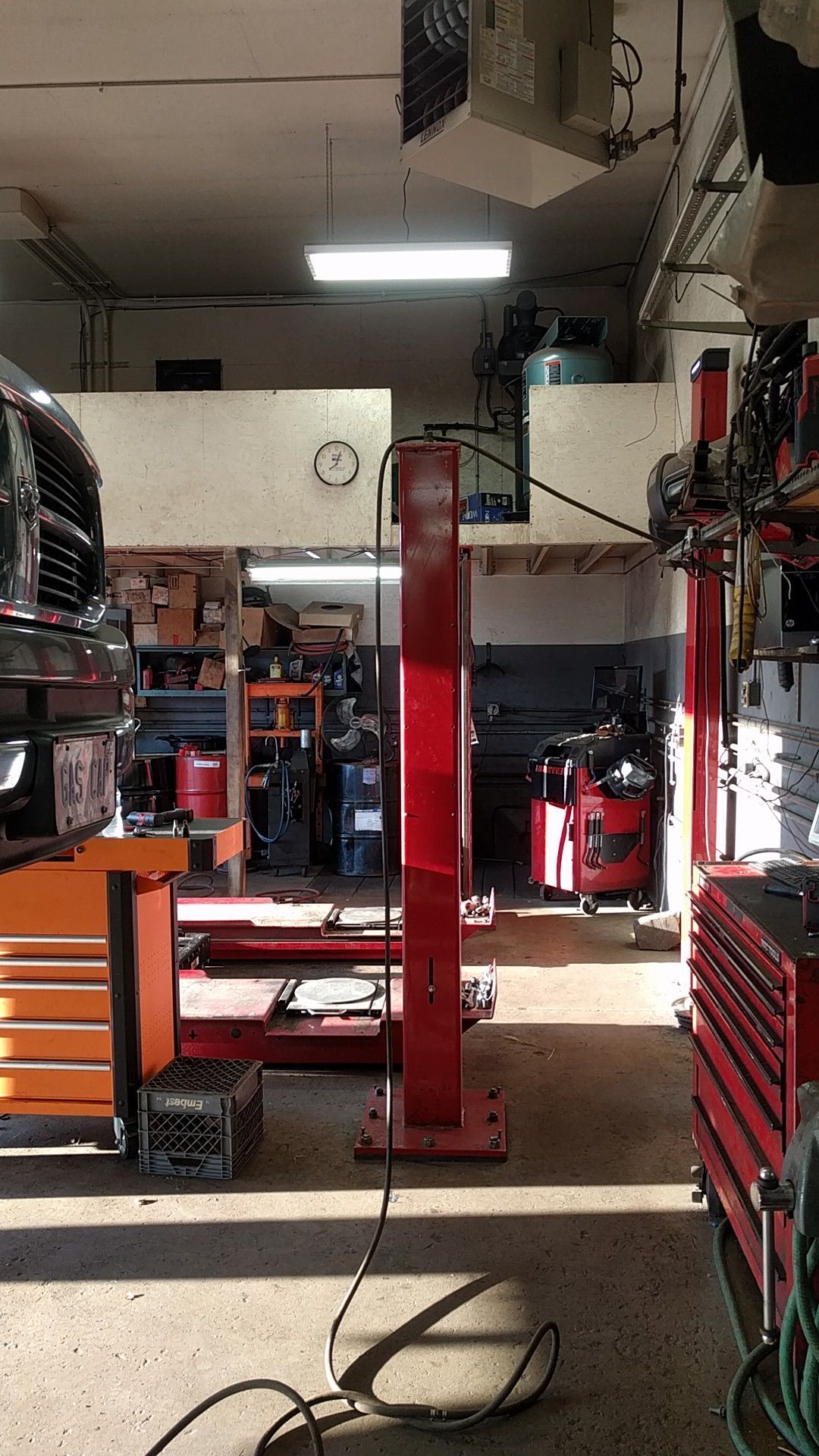 A car lift in a mechanic's shop with tools and equipment, lit by overhead lights. | Railside Auto Service