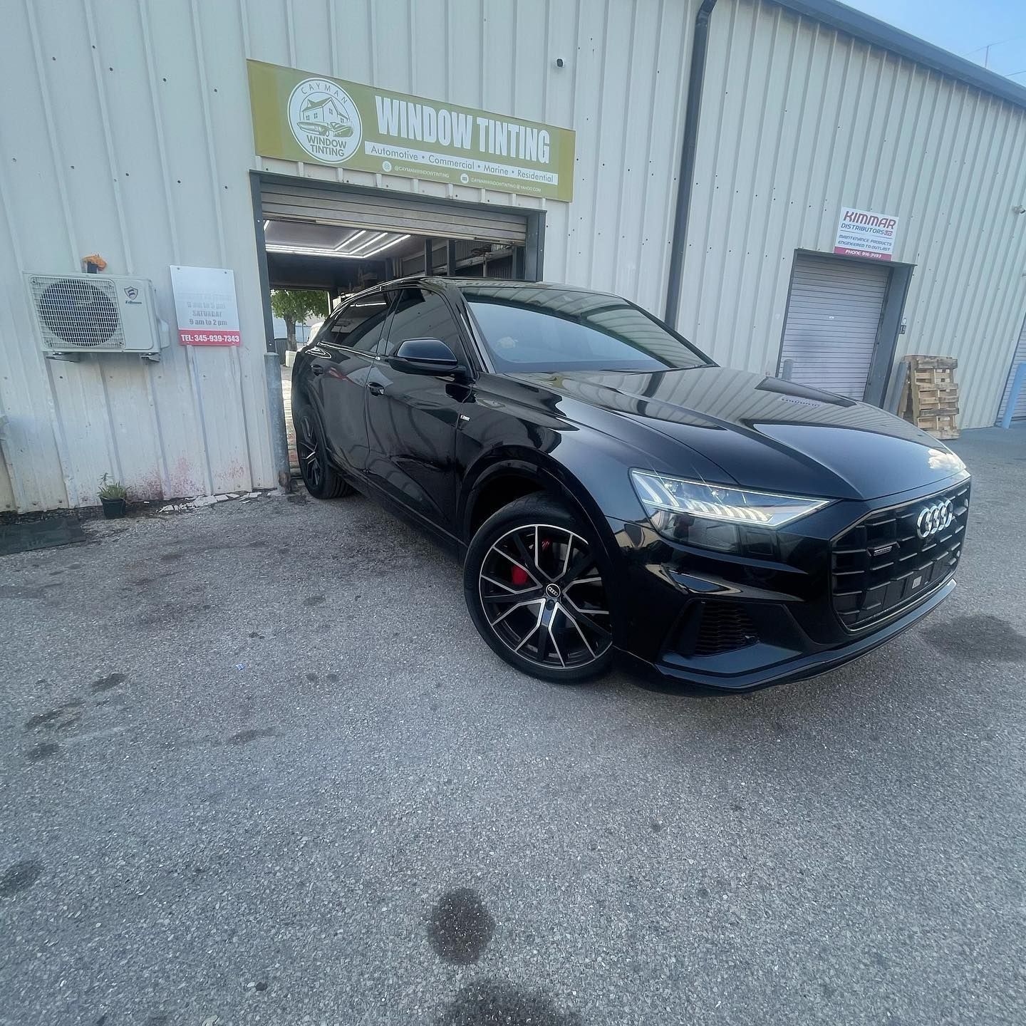 Black sedan parked outside an industrial garage with a sign above the entrance
