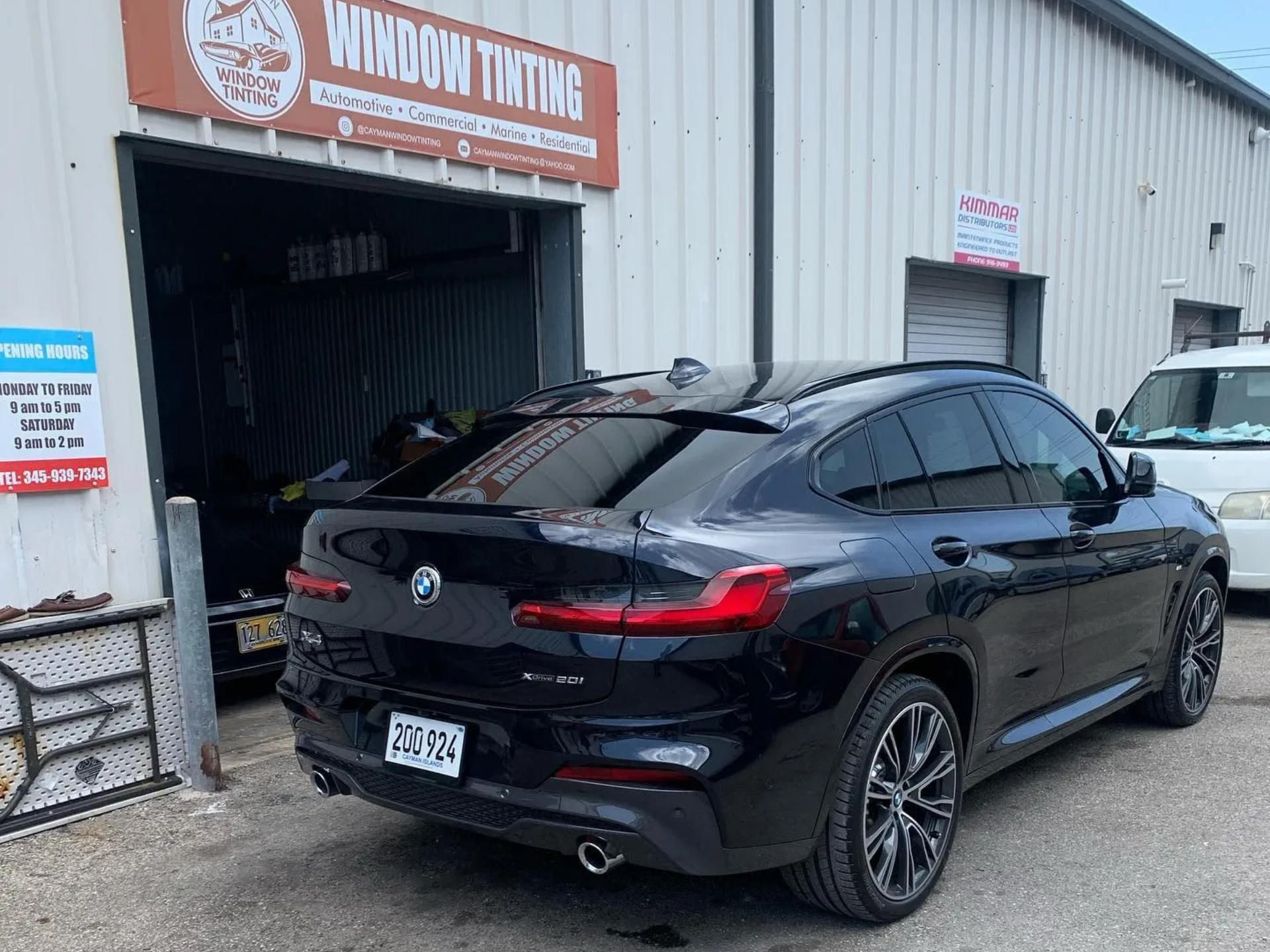 Black BMW SUV with tinted windows parked outside a window tinting shop.