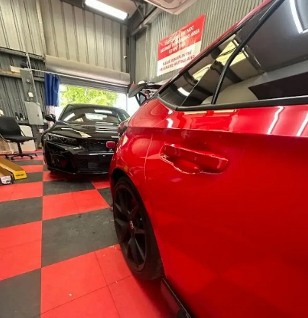Close-up of a red car with a high-gloss ceramic coating inside an auto detailing shop.