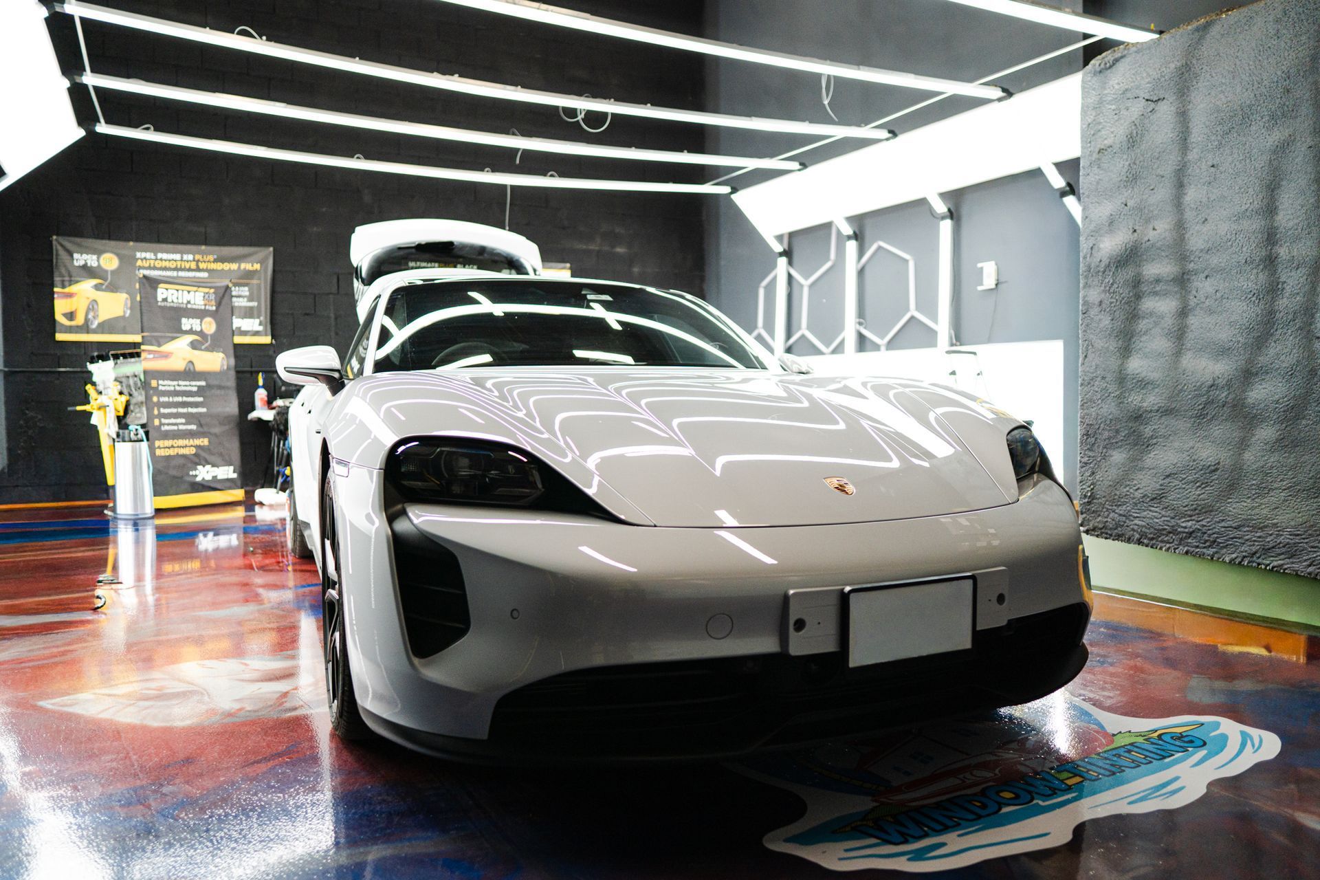 White Porsche Taycan in a car detailing studio, hood and doors open.