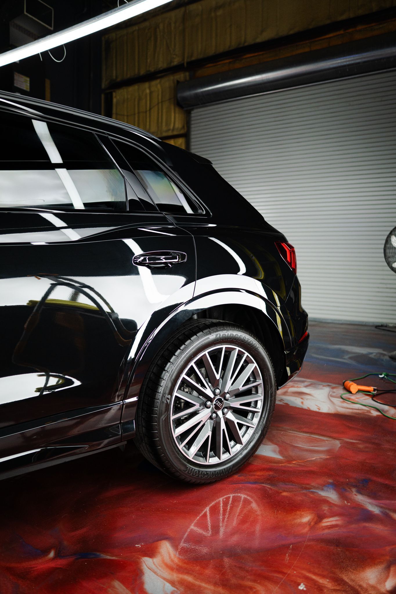 Black SUV parked in a garage with a glossy, reflective finish. Red epoxy floor.