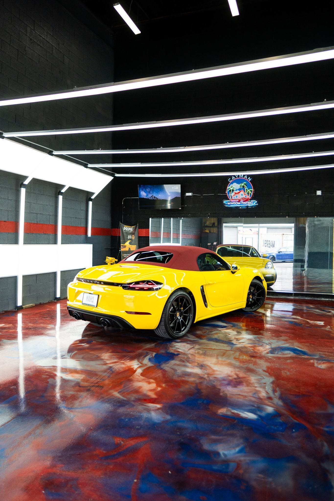 Yellow convertible car in a brightly lit garage with a reflective epoxy floor.