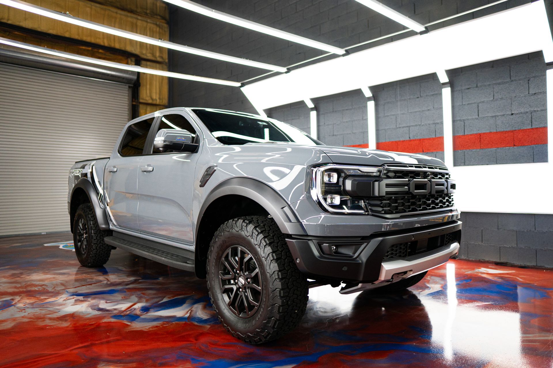 Gray Ford Ranger Raptor pickup truck in a brightly lit garage.