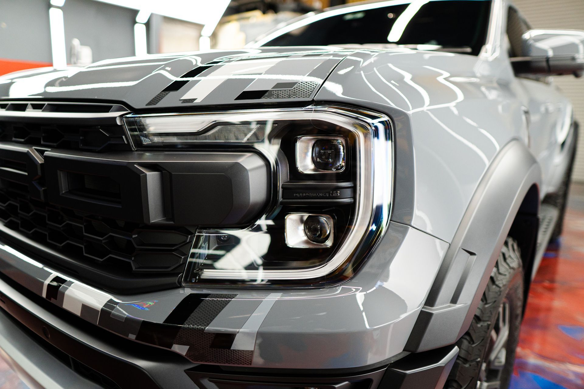 Gray Ford truck with black grill, headlight detail.