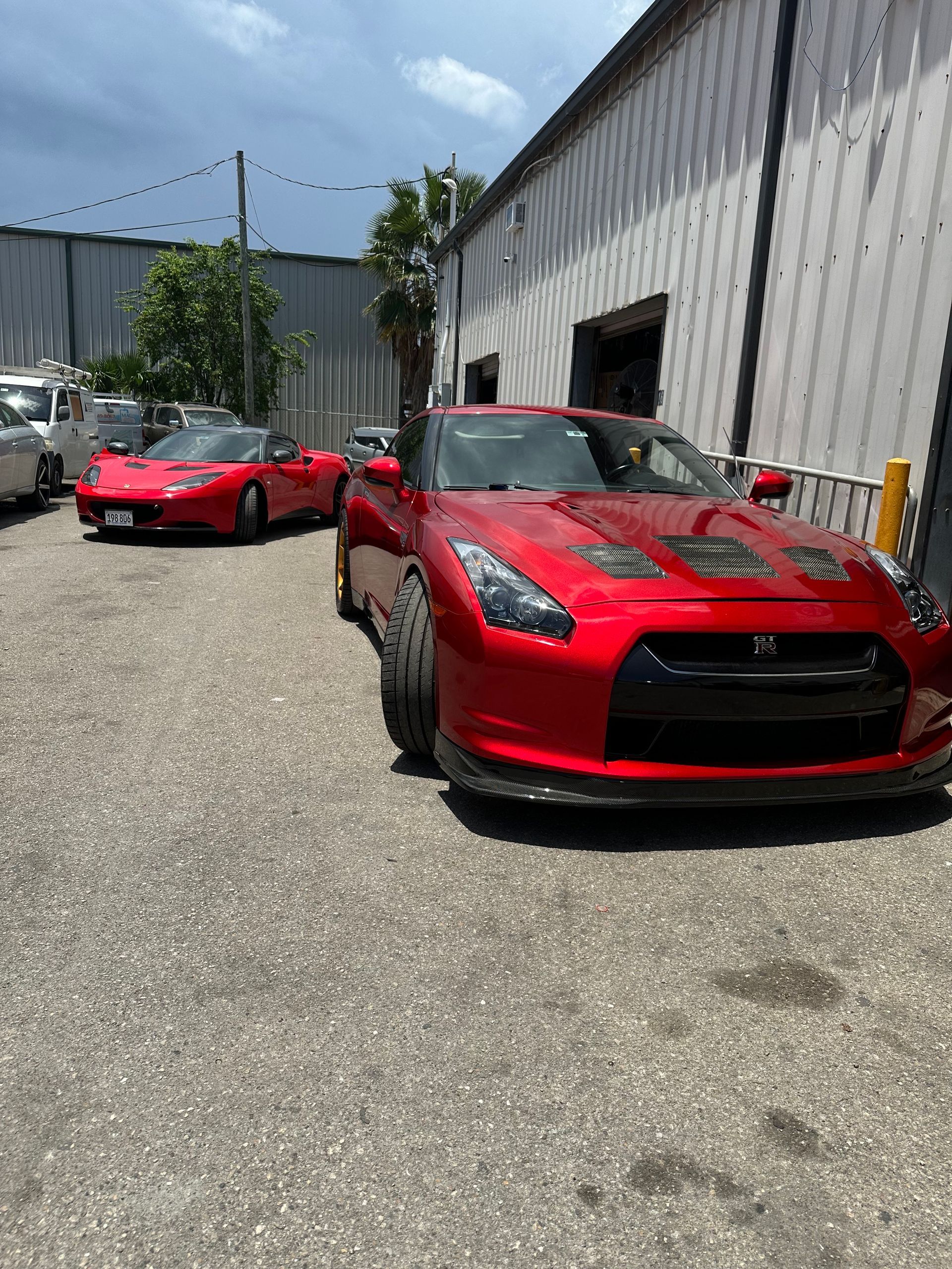 Red Nissan GT-R and red Honda NSX parked outside a building on a sunny day.