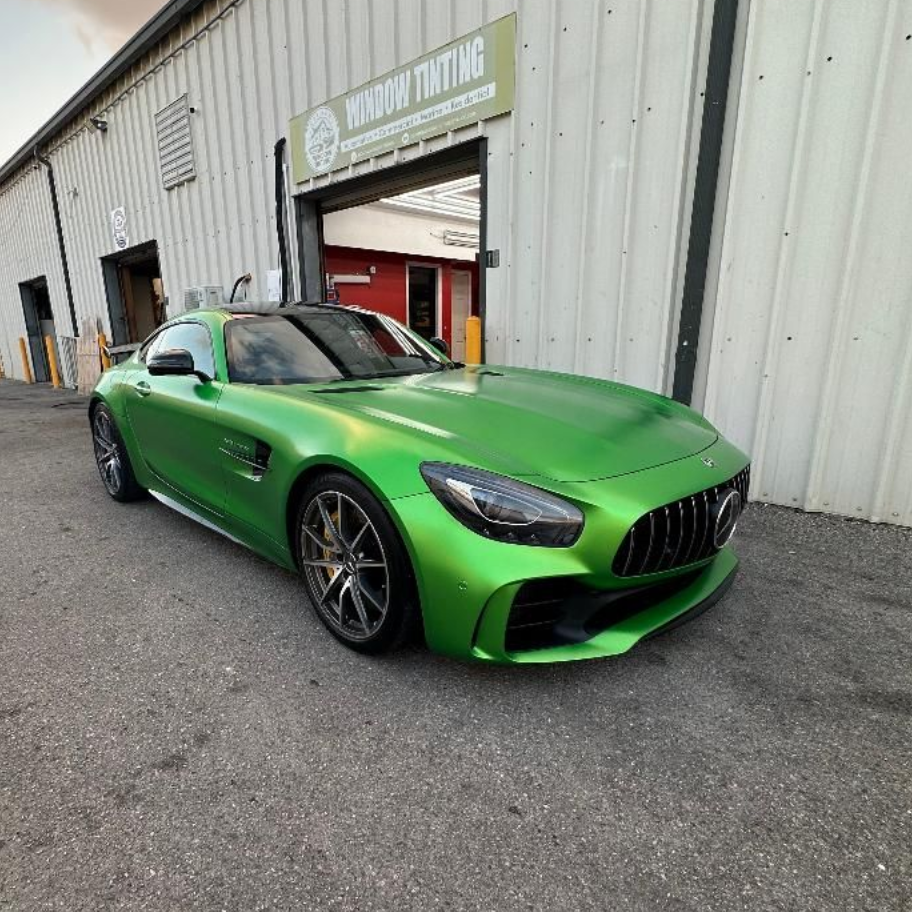 Green Mercedes-AMG GT sports car parked in front of a 