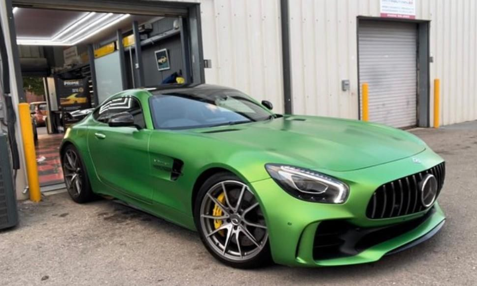 Green Mercedes AMG GT parked in a garage, sporting yellow brake calipers.