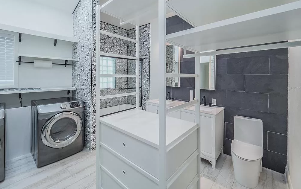 Laundry room with washer, shelving, white vanity, and toilet.