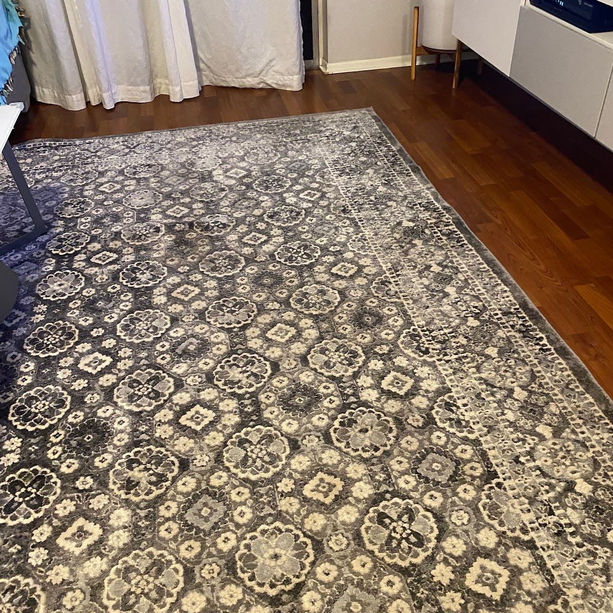 Gray patterned rug on dark wood floor.