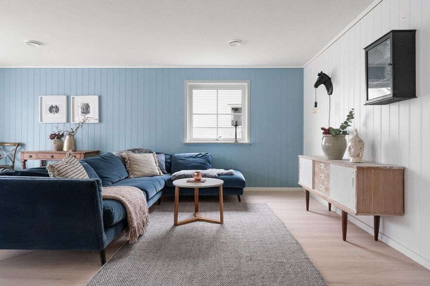 Blue-walled living room with a navy sectional, a light rug, and a wooden console table with a black horse head on wall.