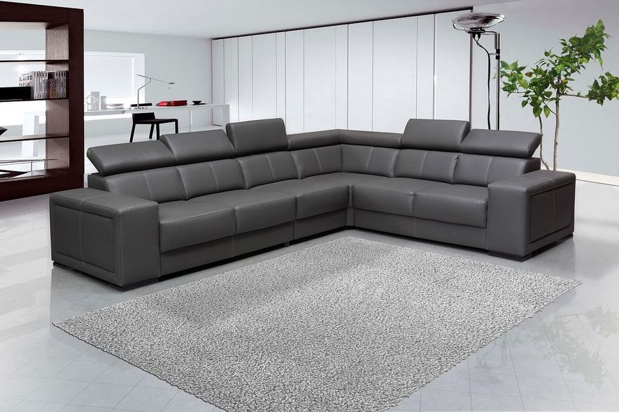 Gray leather sectional sofa on a gray rug in a modern, minimalist living room.