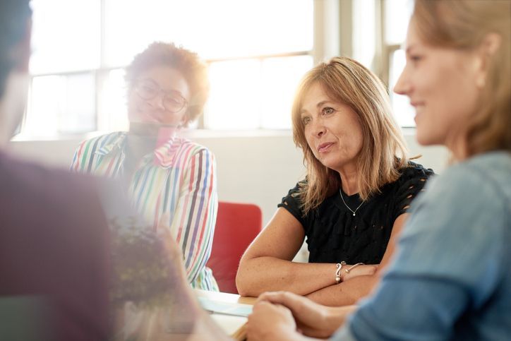 Um grupo de mulheres está sentado ao redor de uma mesa em uma reunião.