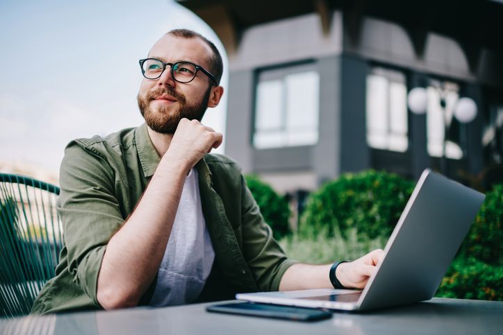 Um homem está sentado a uma mesa usando um laptop.