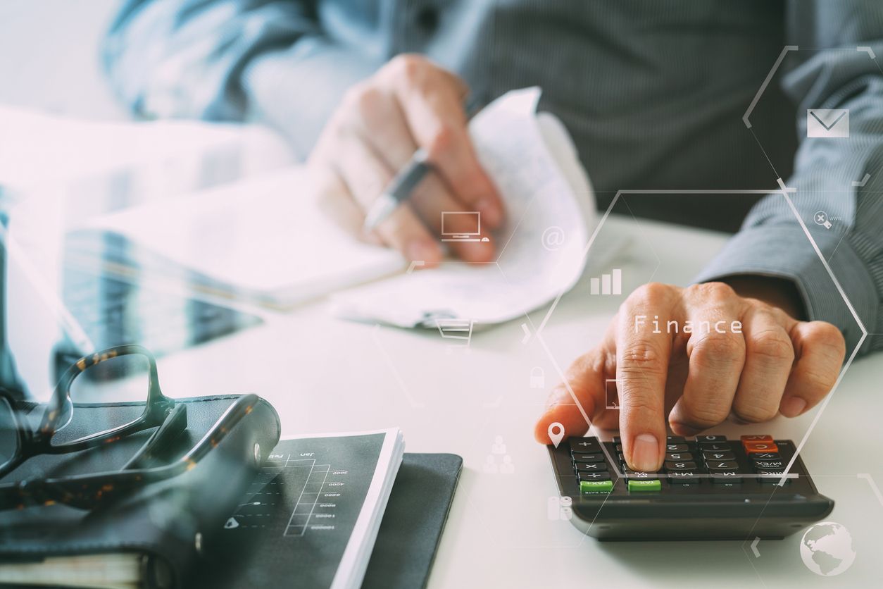 homem fazendo cálculo em calculadora e com papel na mão