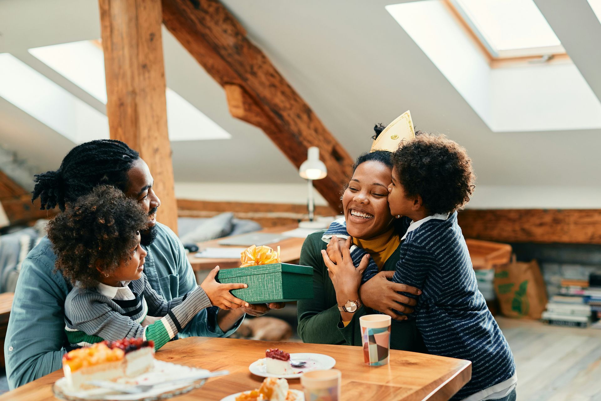 A family is sitting at a table with a cake and a gift.