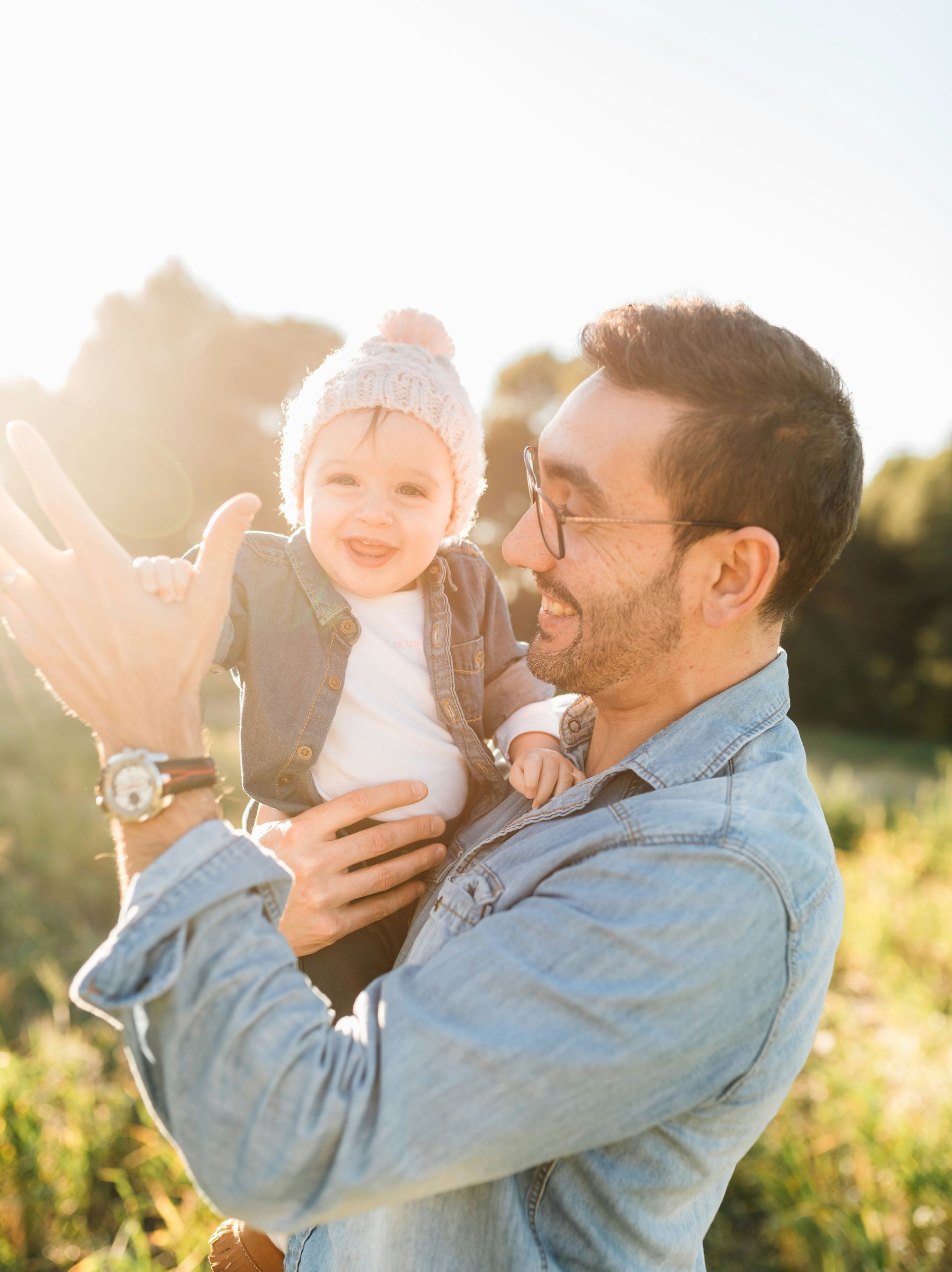 A man is holding a baby in his arms in a field.