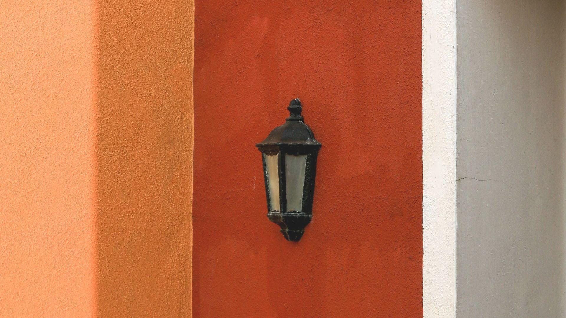 A black lamp is hanging on a red wall.