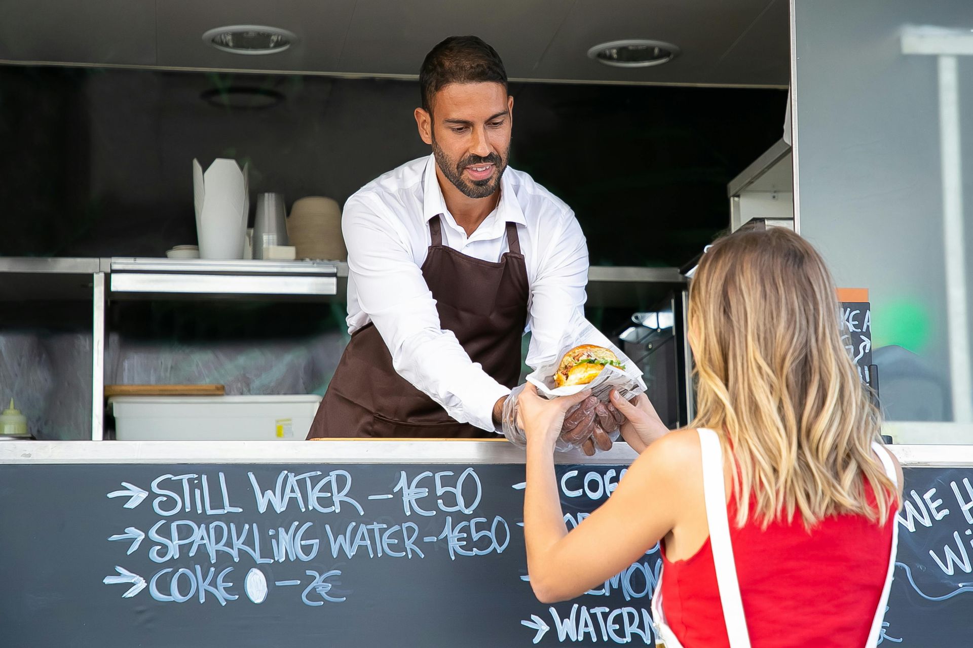 A man is serving food to a woman at a food truck.