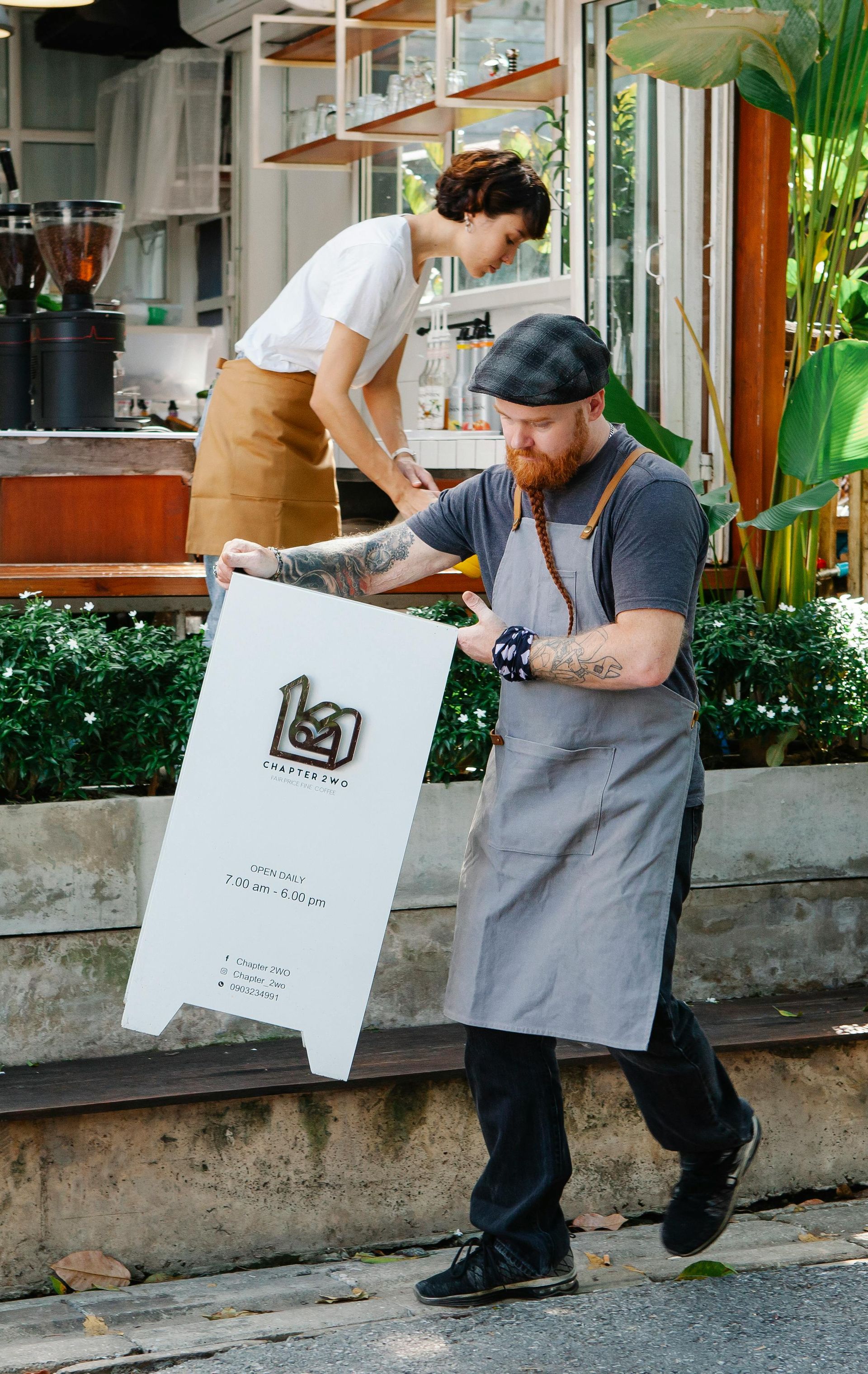 A man in an apron is carrying a large white sign.