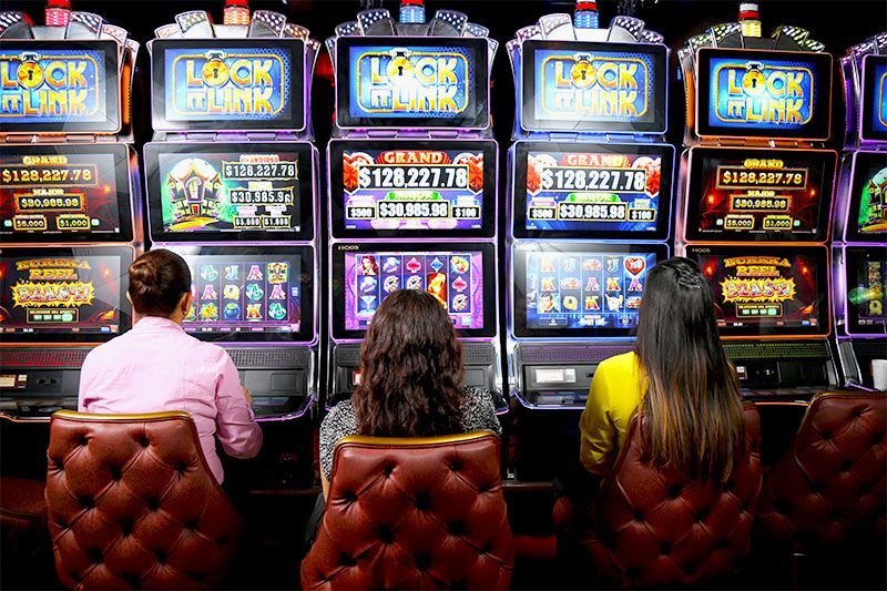 Tres mujeres están jugando a las máquinas tragamonedas en un casino.