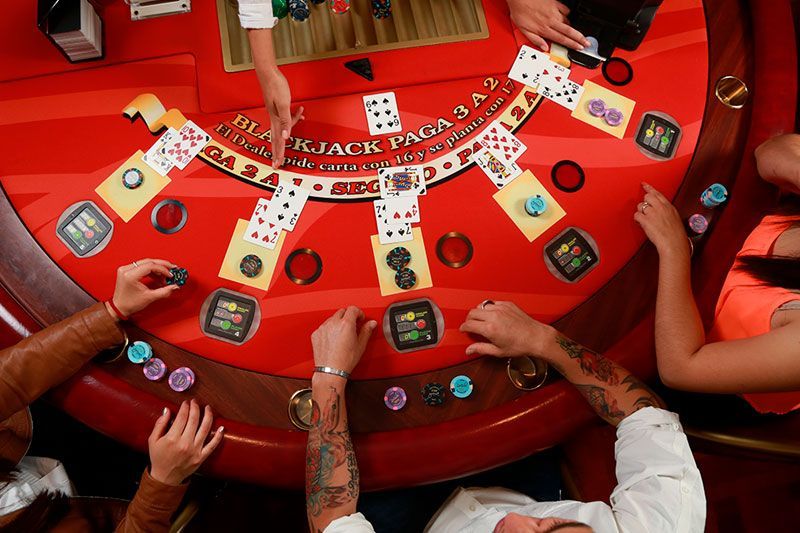 Un grupo de personas está jugando una partida de blackjack en un casino.