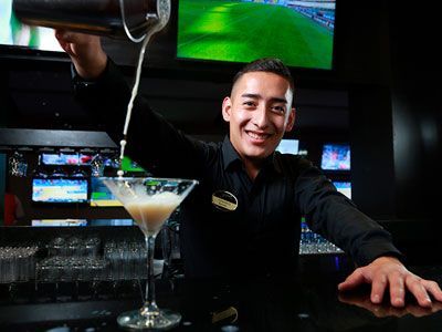 Un camarero está sirviendo una bebida en una copa de martini.