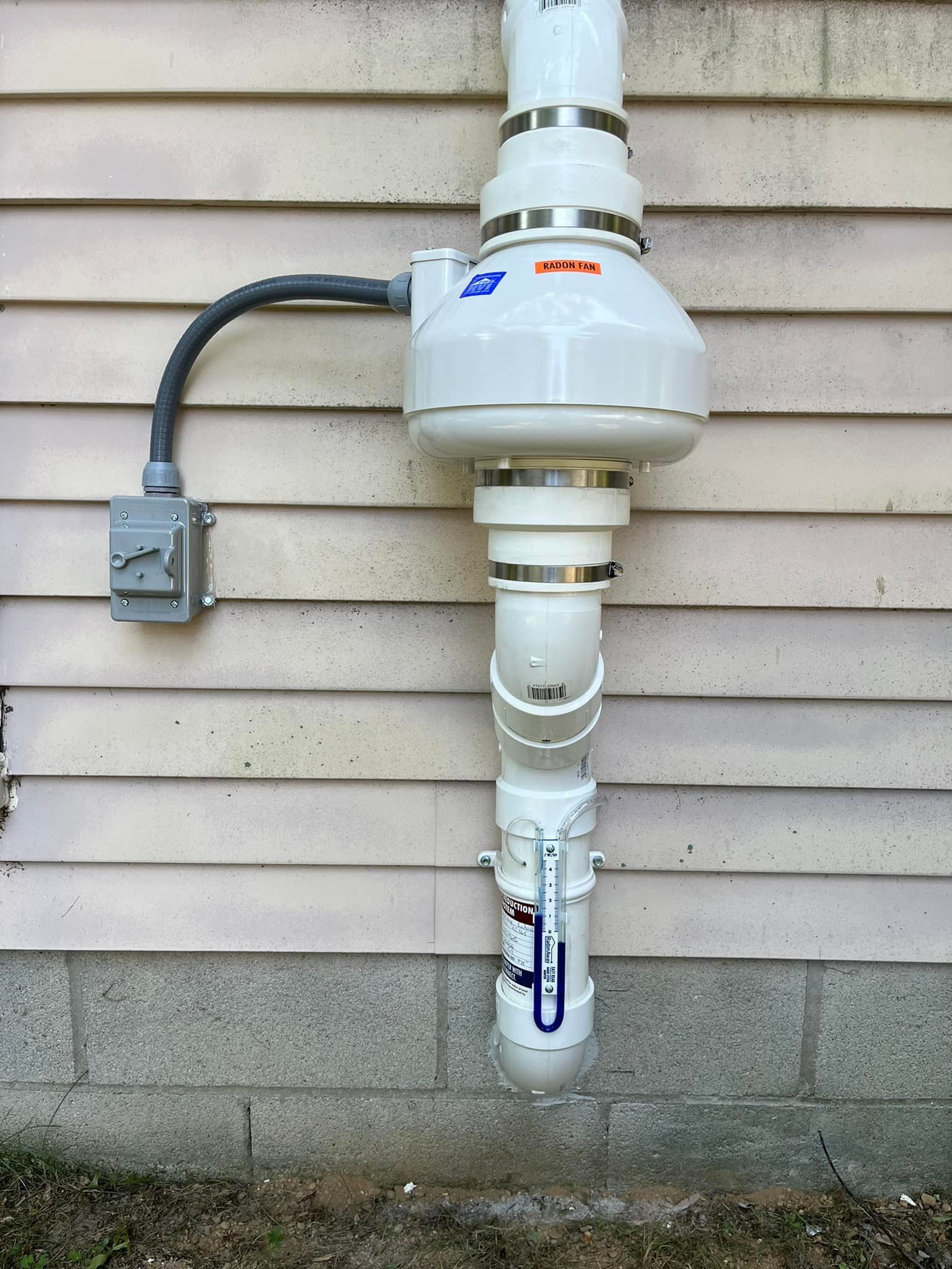 A white pipe is attached to the side of a house.