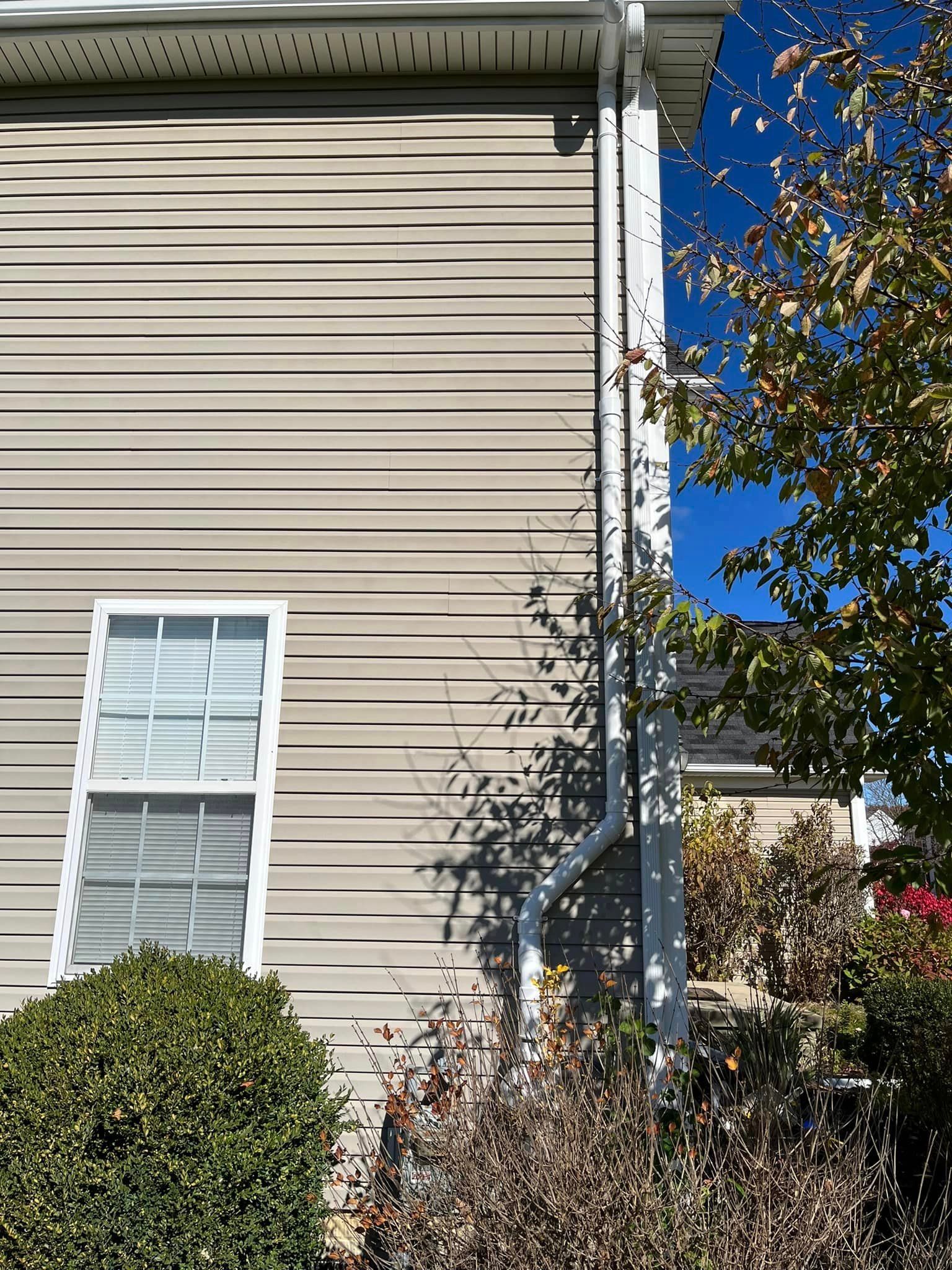 The side of a house with a window and a gutter.